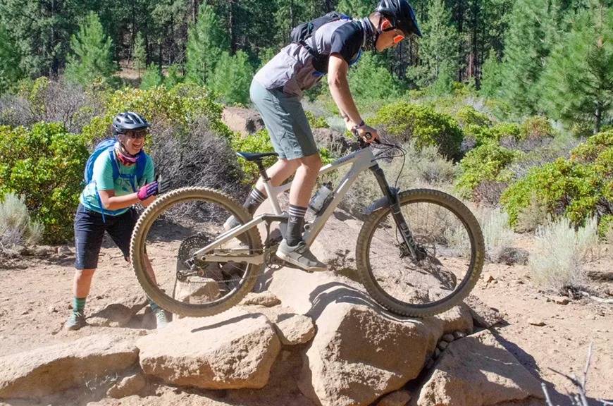 Mountain biking over a rock obstacle with Grit Clinics Profesional MTB Skills Coach