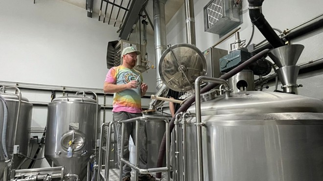 Man stands in front of brewery tanks