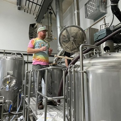 Man stands in front of brewery tanks