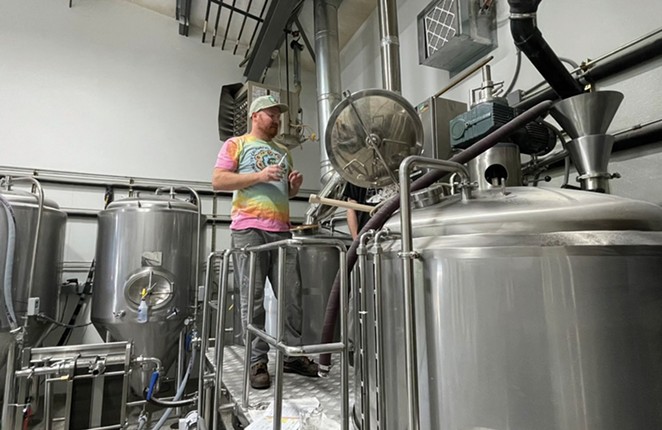 Man stands in front of brewery tanks