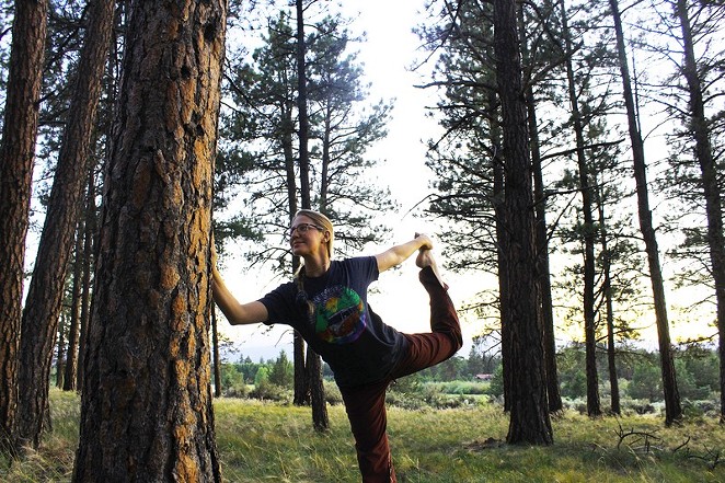 A yoga participant smiles while in a pose connected to the trees at Indian Ford Meadow Preserve.